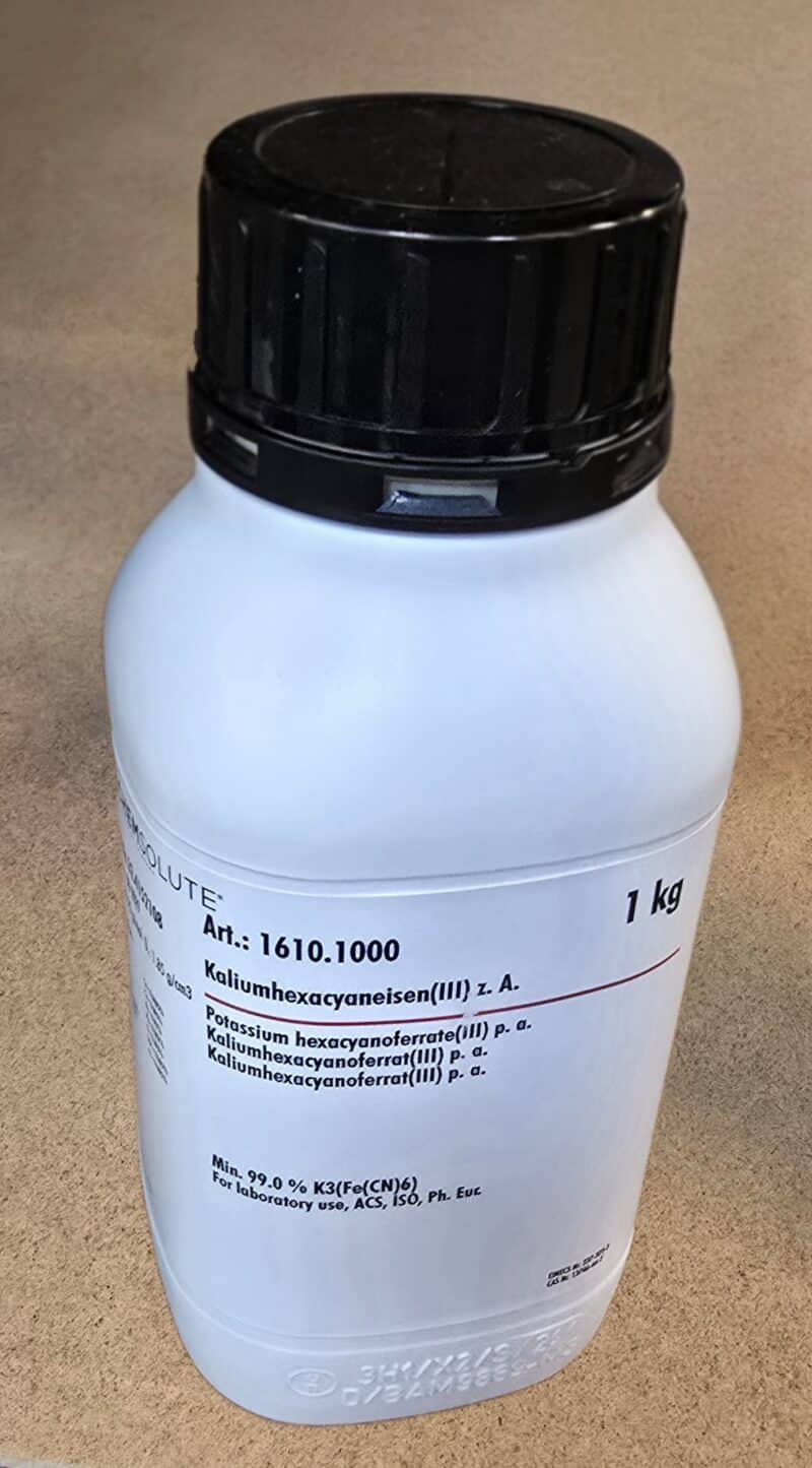 En hvid 1 kg flaske mærket "Kaliumhexacyanoferrat (III) 0,1 M opl." med produktinformation på flere sprog.
