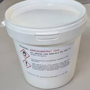 En hvid plastbeholder med Ammoniumnitrat 800 g med faresymboler og sikkerhedsoplysninger på etiketten, placeret på en grå overflade.