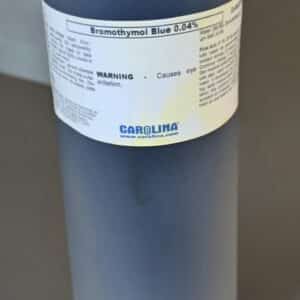 En 1L plastflaske med Bromthymolblåtopløsning 0,04% med sort hætte og mørkeblå væske på en grå overflade.