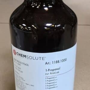 En mørk glasflaske mærket Propan-1-ol p.a. (1 liter) med faresymboler, stregkode og kemiske data på en hvid etiket.