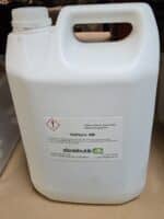 En hvid 5L Saltsyre 4M-beholder i plast med faresymbol og dansk tekst står på en beige overflade.