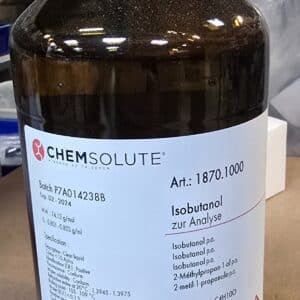 En brun glasflaske mærket 2-Methylpropan-1-ol (1 L, p.a.) med faresymboler og detaljer på en laboratorieoverflade.