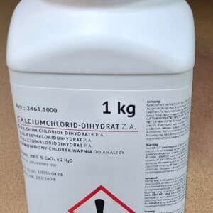 En hvid plastbeholder med rød hætte mærket "Calciumchlorid dihydrat, ren (1 kg)" og med fare- og instruktionstekst.
