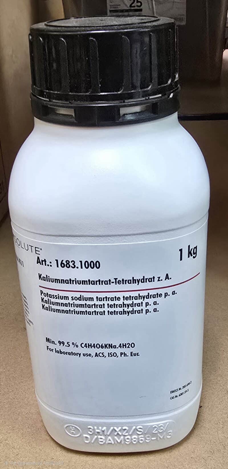 En hvid 1 kg flaske mærket Kaliumnatriumtartrat med produktinformation og renhedsdetaljer på forsiden.