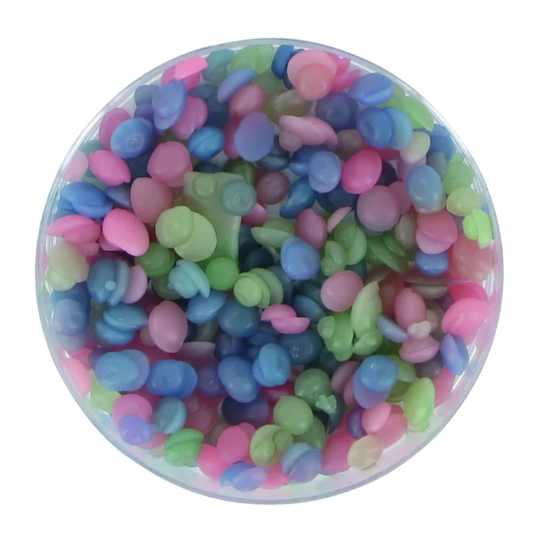 Et Delvis fusionssæt: en klar rund beholder med små pink, blå, grønne og lilla plastikbrikker.