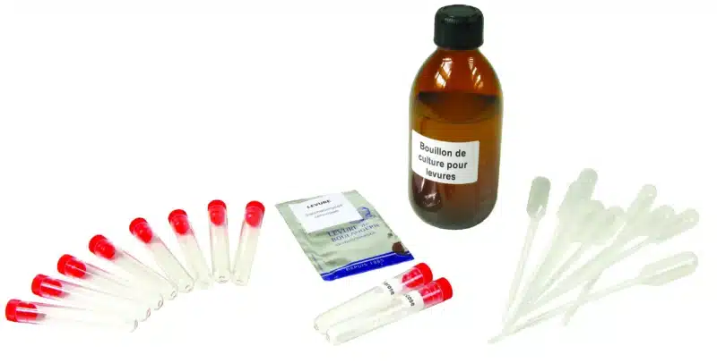 Et Mikrobiologisk initieringssæt - Gær med reagensglas, pipetter og en lille pakke står på en hvid flade.