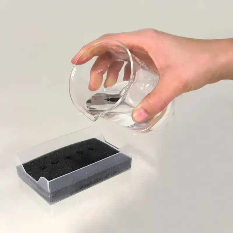 En hånd hælder vand på Kølet stativ til PCR-mikrorør, der er placeret i en klar plastbakke.