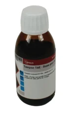 En brun glasflaske med en hvid hætte mærket TAE-buffer - Dosis til 1L og sikkerhedsinstruktioner på fransk.