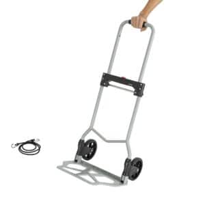 En hånd holder den sammenklappelige tohjulede Sækkevogn med en sort elastiksnor ved siden af på en hvid baggrund.