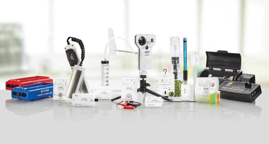 En række videnskabelige instrumenter og laboratorieudstyr er anbragt på en reflekterende overflade mod en sløret baggrund.