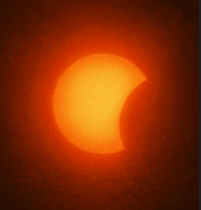 Skærmbillede 2026-08-13 143932 - LabDidakt.dk En delvist formørket sol i form af en halvmåne, omgivet af et orange skær på en mørk baggrund.