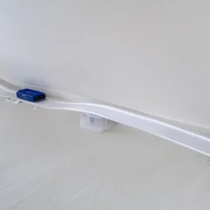 »Flexibane til Smart Cart«, en hvid plastbane med en blå bil, strækker sig hen over et hvidt gulv og er understøttet af kasser og beholdere.